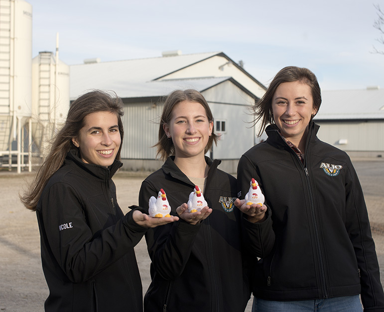 3 young women  smiling and holding CFO chicken toys