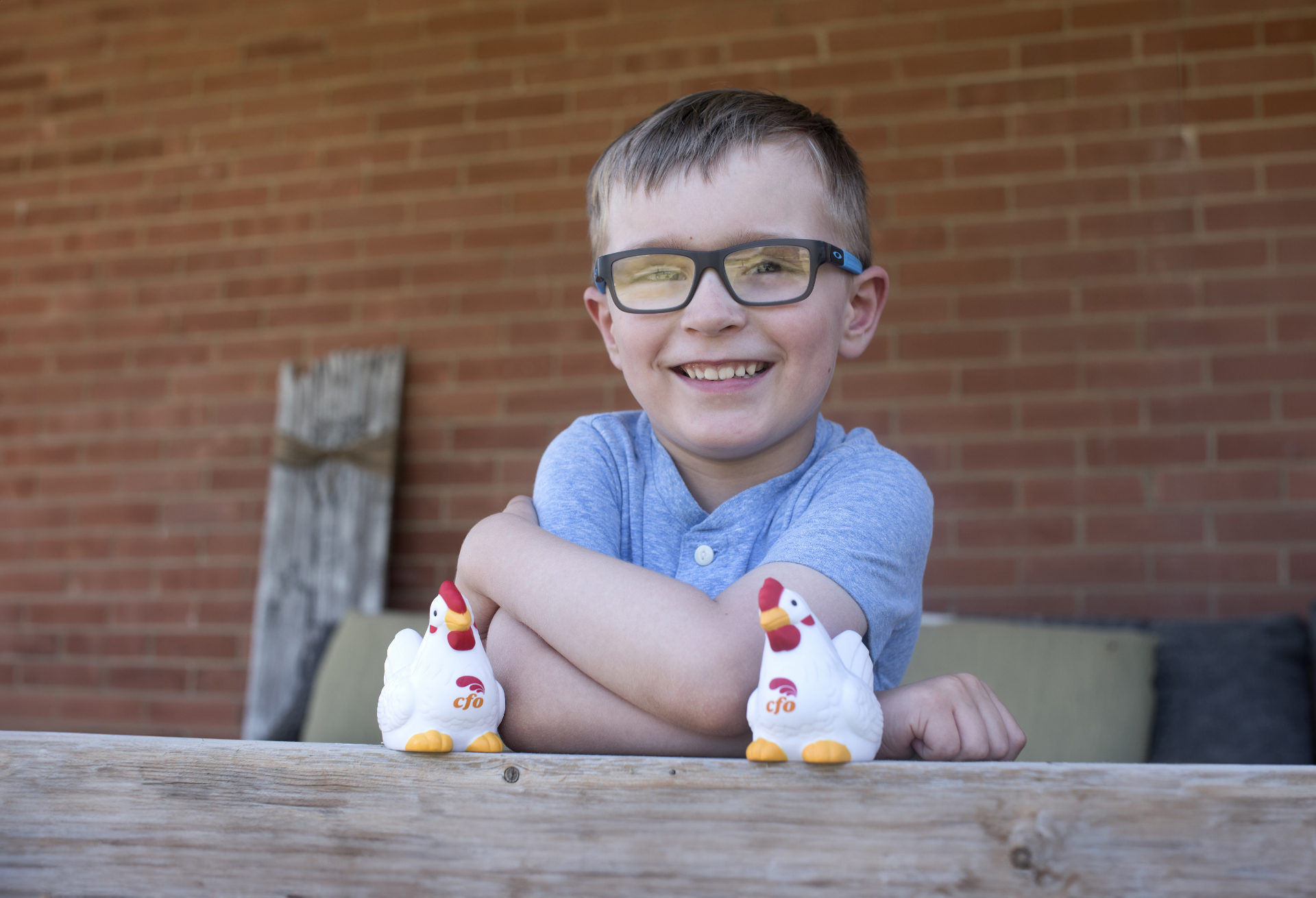 A young boy smiling at the camera with a CFO chicken toy in front of him