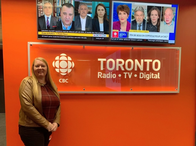 Andrea Veldhuizen posing in front of a CBC logo at the CBC studio
